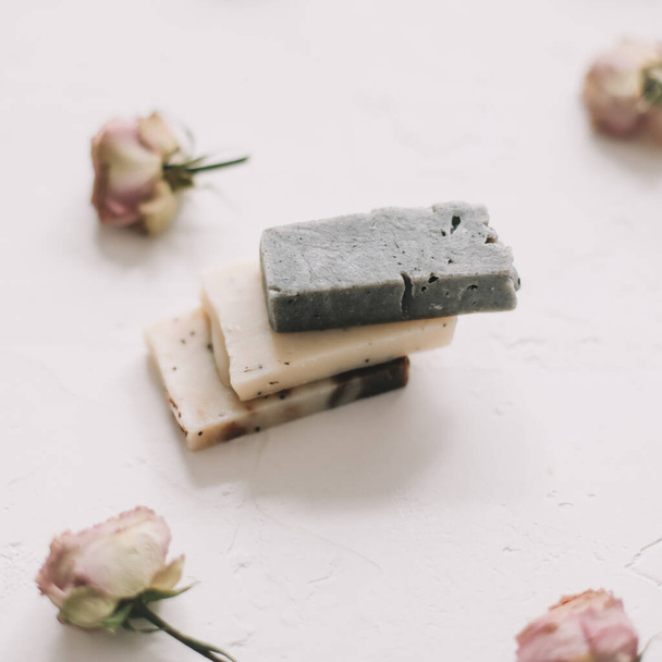 Soap bars with dry roses on white background. Handmade floral soap with rose buds. Natural cosmetics. flat lay, top view - Valokuva, kuva