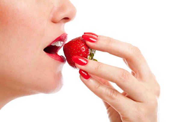 Beautiful woman taking a bite of a ripe red strawberry - Fotoğraf, Görsel