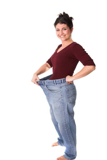 happy brunette woman showing weight loss and wearing huge denim jeans pants  - Foto, Bild