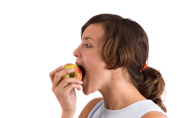 Pretty brunette taking a healthy bite out of a rosy apple - Photo, Image