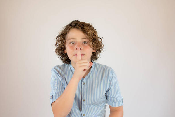 Menino com camisa azul fazendo um gesto de silêncio - Foto, Imagem