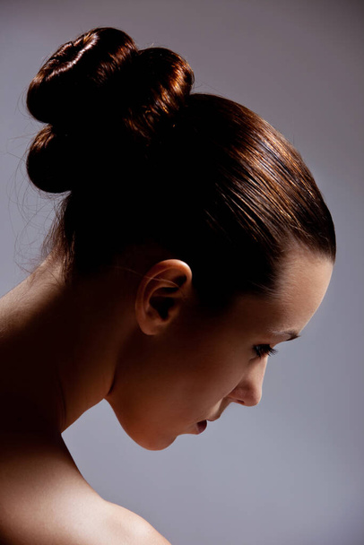 Beautiful brunette woman model posing in studio, hair bun hairstyle  - Foto, Bild