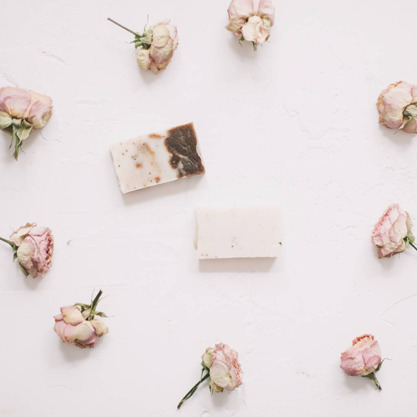 Soap bars with dry roses on white background. Handmade floral soap with rose buds. Natural cosmetics. flat lay, top view - Foto, Imagem