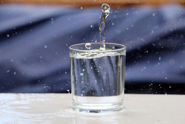 A closeup shot of a glass of water with splashes on a white surface - 写真・画像