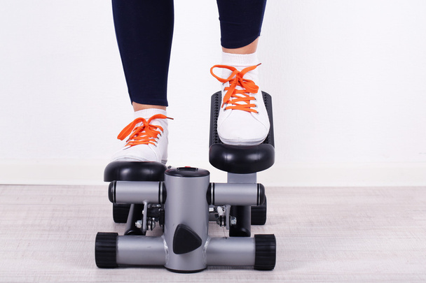Woman doing exercise on stepper. Close-up on legs. - Foto, Imagen