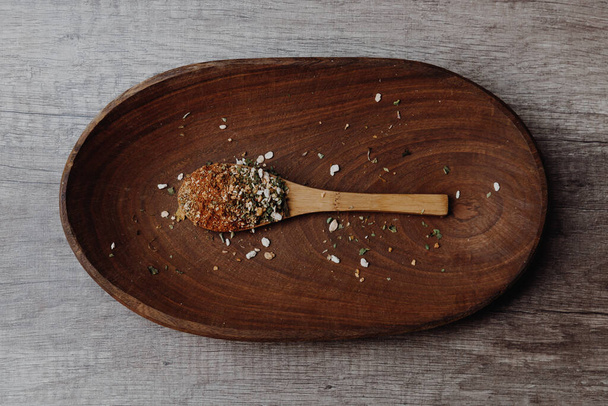 A high angle closeup shot of crushed nuts on a wooden spoon in a wooden plate - Fotoğraf, Görsel
