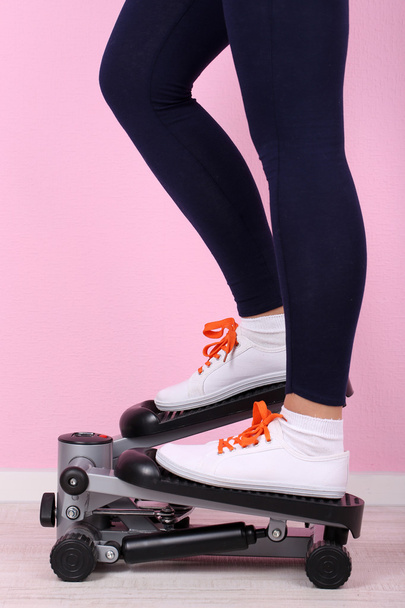Woman doing exercise on stepper. Close-up on legs. - Foto, Imagen