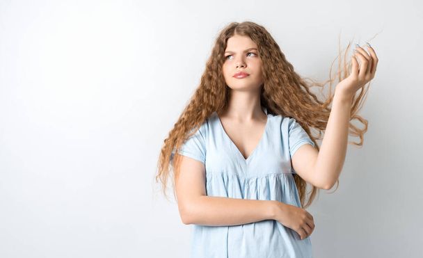 Portrait of attractive european girl, discontentedly tilting head and shaking curly hair. Isolated over white background. - Photo, Image