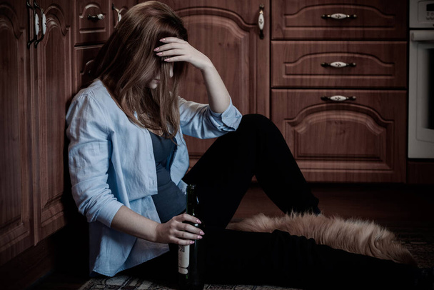 У женщины депрессия, проблема с алкоголем, она сидит на полу на кухне с собакой - Фото, изображение