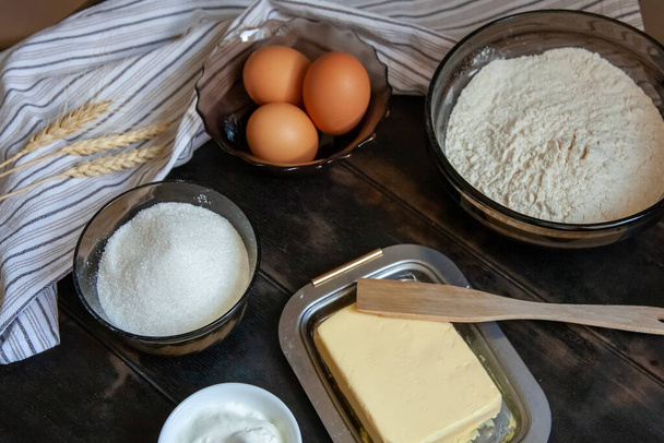 Sütőipari összetevők a rövid tésztához: vaj, liszt, tojás, tejföl, törülköző fából készült háttérrel. Lapos felülnézet. - Fotó, kép