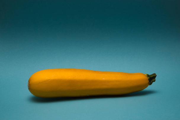 isolated closeup close up of a yellow courgette on a blue background, Ger - Foto, Bild