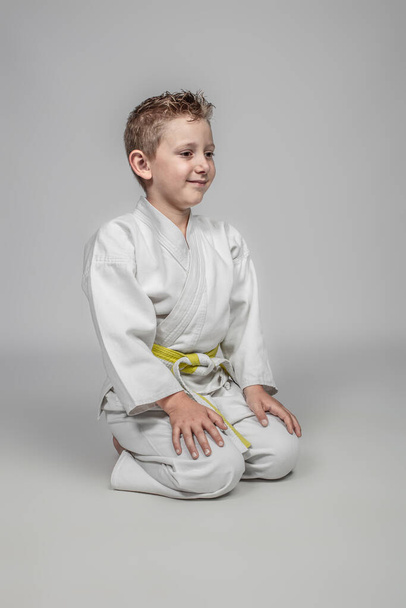 child practicing karate in sitting position in Japanese style. studio portrait - Fotoğraf, Görsel
