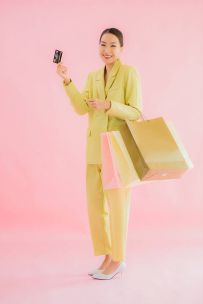 Portrait beautiful young asian business woman with shopping bag on color isolated background - Фото, зображення