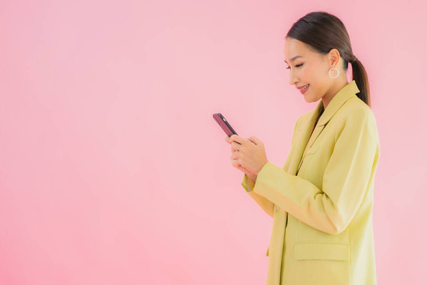 Muotokuva kaunis nuori aasialainen liike nainen käyttää älykästä matkapuhelinta kahvikuppi värillinen tausta - Valokuva, kuva