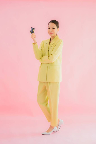 Porträt schöne junge asiatische Geschäftsfrau mit Kreditkarte auf farbigem Hintergrund - Foto, Bild