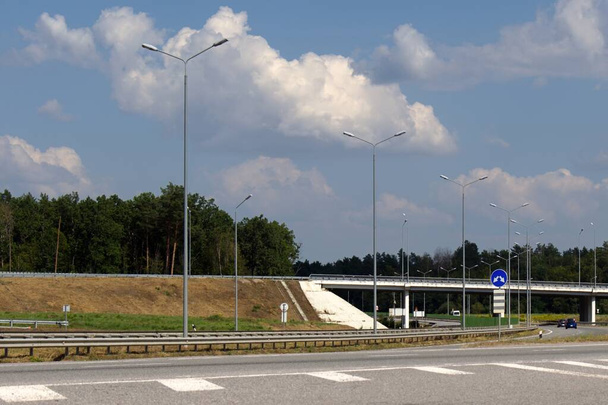 об'їзд по автомагістралі, освітлення стовпів вздовж дороги, розмитий передній план, блакитне небо з білими хмарами
 - Фото, зображення