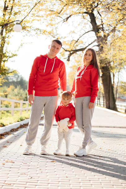 Happy young family in the autumn park. mom, dad and little daughter enjoying life together outdoors. People having fun in nature. Mother's, father's, child's day - Photo, Image