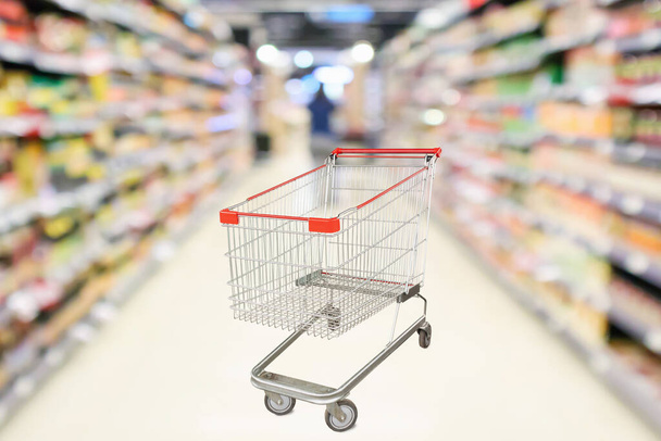 Leere Einkaufswagen mit abstrakten Unschärfen Supermarkt Discounter Gang und Produktregale Innenraum defokussiert Hintergrund - Foto, Bild