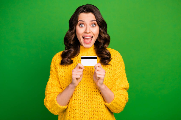 Photo of pretty excited funny lady open mouth holding credit card wireless online money payment wear knitted yellow pullover isolated bright green color background - Foto, Imagen