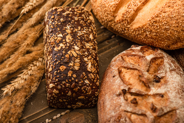 fresh baked bread loaves with spikelets on wooden surface - Valokuva, kuva
