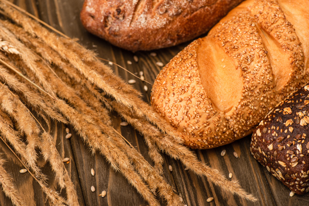vers gebakken brood broden met spikeletten op houten ondergrond - Foto, afbeelding