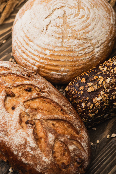 zblízka pohled na čerstvé pečené chlebové bochníky na dřevěném povrchu - Fotografie, Obrázek