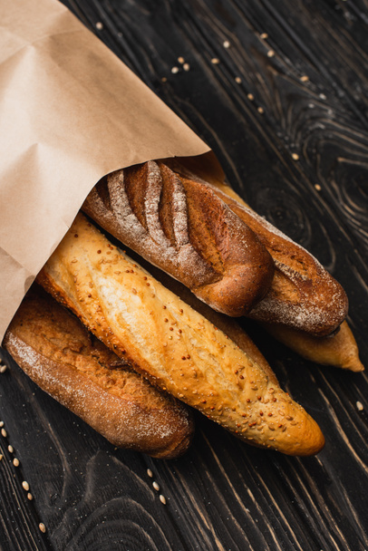 fresh baked baguette loaves in paper bag on wooden surface - Zdjęcie, obraz