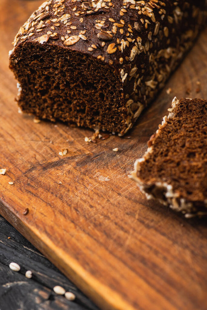 vue rapprochée du pain cuit frais brun coupé sur une planche en bois - Photo, image