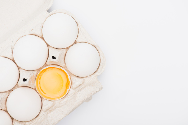 vista superior de huevos de pollo frescos y yema en caja de cartón aislada en blanco - Foto, Imagen