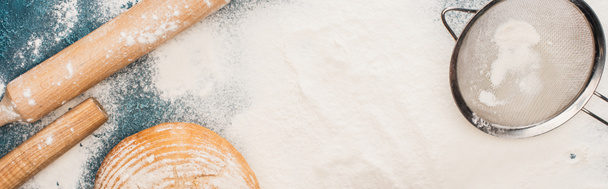 felülnézet a friss kenyérpirítóból a sodrófa közelében és szitán liszten, panorámás felvétel - Fotó, kép