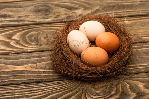 fresh chicken eggs in nest on wooden surface - 写真・画像