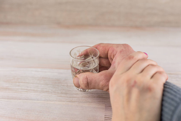 perheongelma alkoholismi: vodka pahoinpideltyjen miesten laukaus, naisen käsi pitää miestä kädestä, kieltäen alkoholin juomisen - Valokuva, kuva