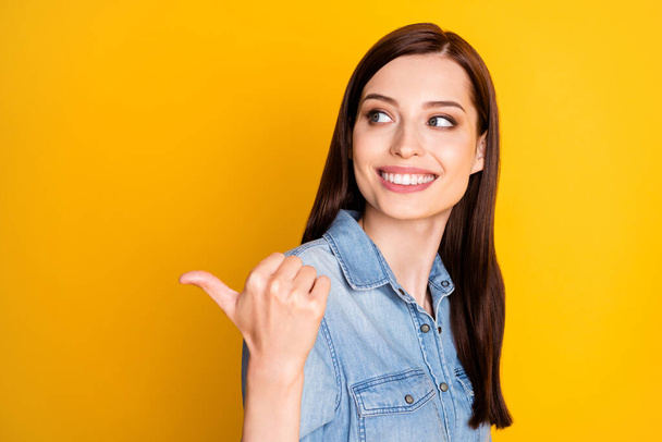 Portrait of positive cheerful girl promoter indicate sales point thumb finger copyspace recommend suggest select adverts promo wear denim jeans outfit isolated over shine color background - Valokuva, kuva