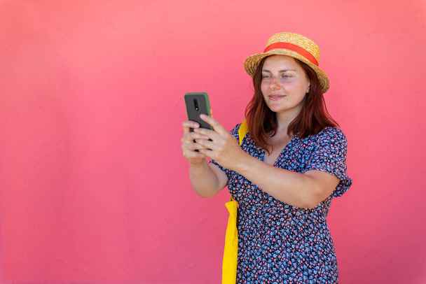 Carefree girl stands near a pink wall in the street taking a selfie - Fotó, kép