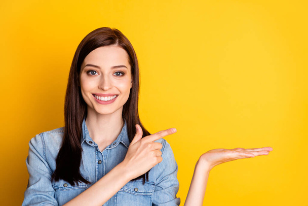 Portrait of positive cheerful girl hold hand point index finger copyspace indicate ads promotion wear good look clothes isolated over bright color background - Фото, зображення