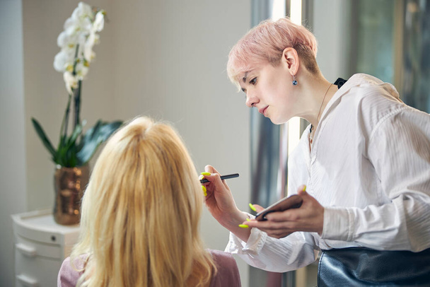 Jovem atenta fazendo maquiagem para seu visitante - Foto, Imagem