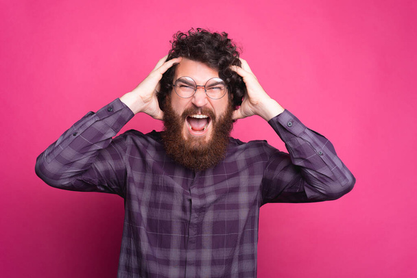 portrét mladého vousatého hipsterského muže křičícího a dívajícího se do kamery - Fotografie, Obrázek