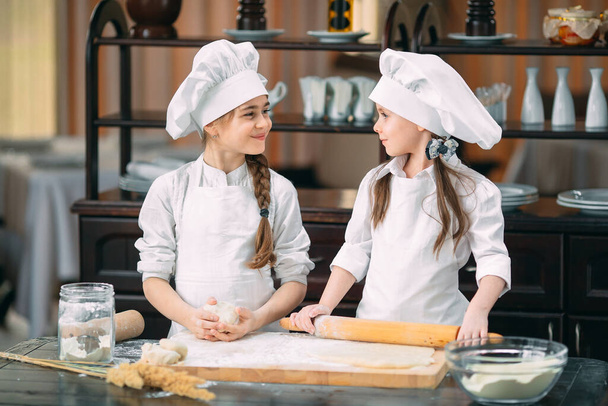 funny girls kids are preparing the dough in the kitchen. - Foto, afbeelding