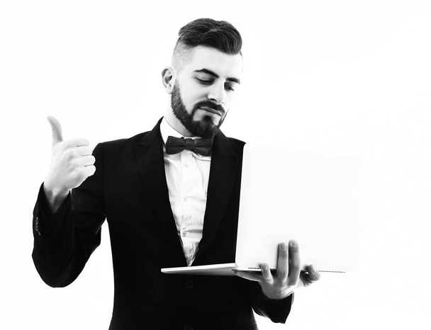 Bearded businessman with moustache holds laptop and shows thumbs up - Foto, afbeelding