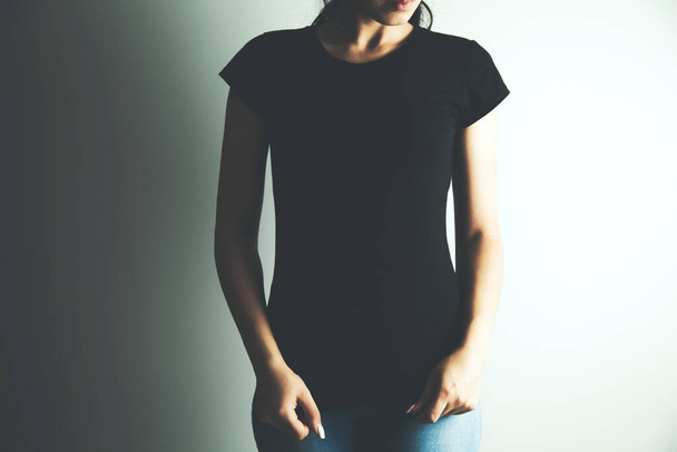 Γυναίκα σε μαύρο t-shirt σε γκρι φόντο - Φωτογραφία, εικόνα