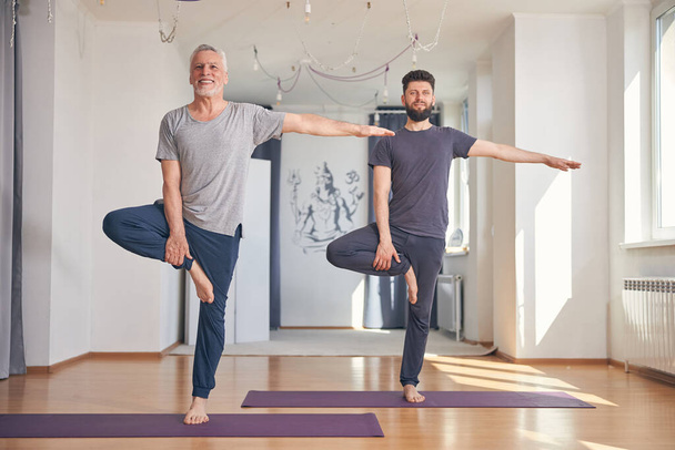 Männer stehen bei der Gleichgewichtsübung auf einem Fuß - Foto, Bild