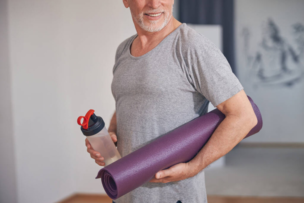Man met een sportfles en een yogamat - Foto, afbeelding