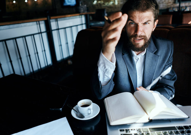 Business man sitting in a cafe in front of a laptop with a cup of coffee work technology lifestyle - Foto, imagen