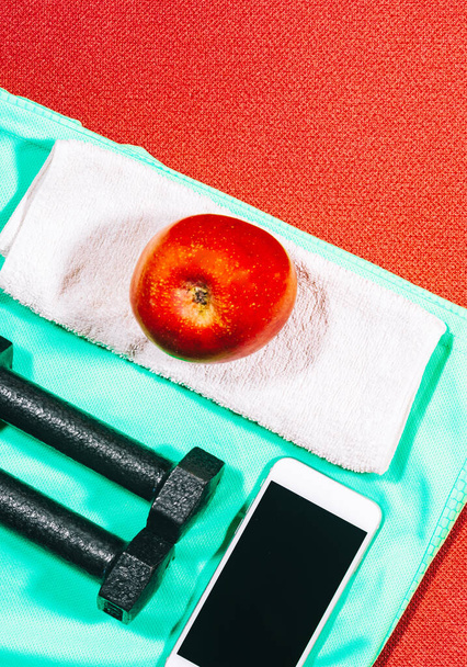 Attribute eines gesunden Lebensstils: Apfel, Sportgeräte, Handy. Werkzeuge für die Fitness zu Hause. - Foto, Bild