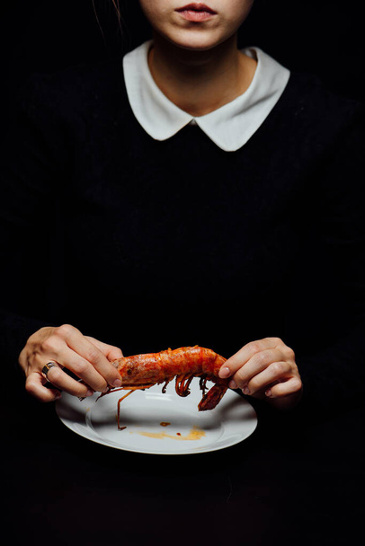 woman and fried lobster on a white plate on a black background - Fotó, kép