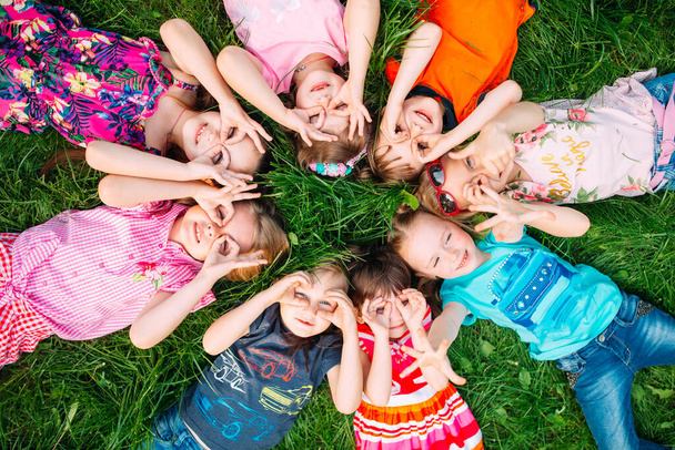 A group of children lying on the green grass in the Park. The interaction of the children. - Foto, Imagem