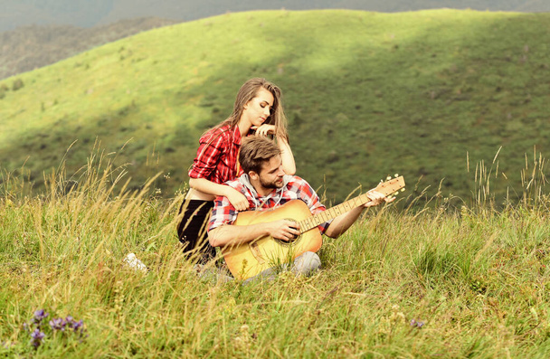 Idyllic place for romantic date. Romantic mood. Couple in love enjoying view from top of mountain. Boyfriend playing guitar. Singing for her. Romantic hike. Romantic couple on summer vacation - Photo, image
