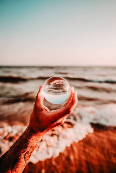 A crystal ball in your hand and the sea landscape in the background. - Fotografie, Obrázek