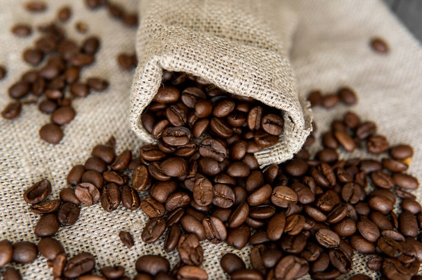 Coffee scattered from a linen bag. Fresh arabica coffee beans on linen textile. - Foto, Imagem