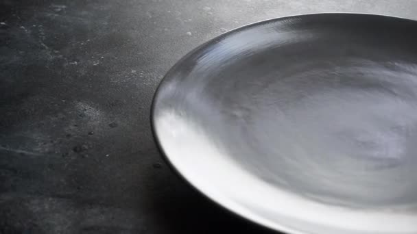 Placa vacía sobre la mesa. Placa de cena gris vacía y tenedor colocado en una mesa en un restaurante o cocina - Metraje, vídeo
